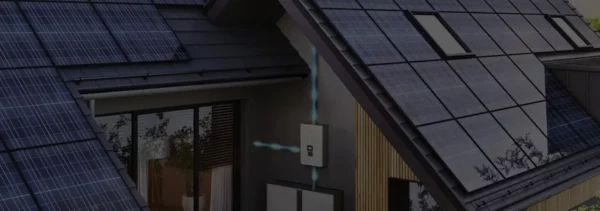Aerial view of modern home with extensive solar panel installation on roof, showing residential microgrid system for energy independence