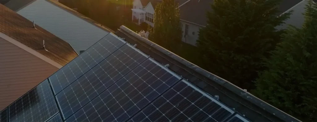 Aerial view of solar panels installed on residential building roof with neighboring houses, demonstrating renewable energy solution for smart home power management