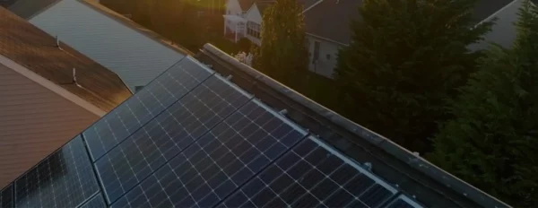 Aerial view of solar panels installed on residential building roof with neighboring houses, demonstrating renewable energy solution for smart home power management