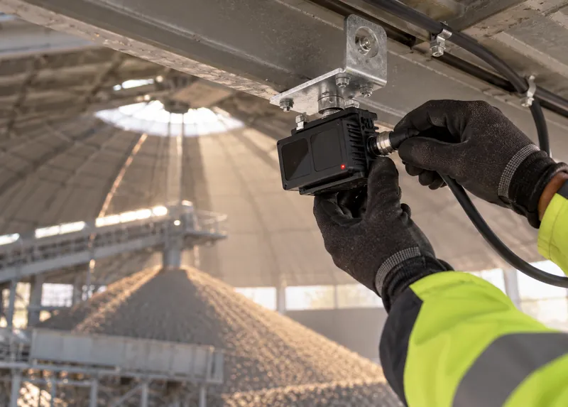 Gloved hands fastening a sensor to a bracket inside a dome